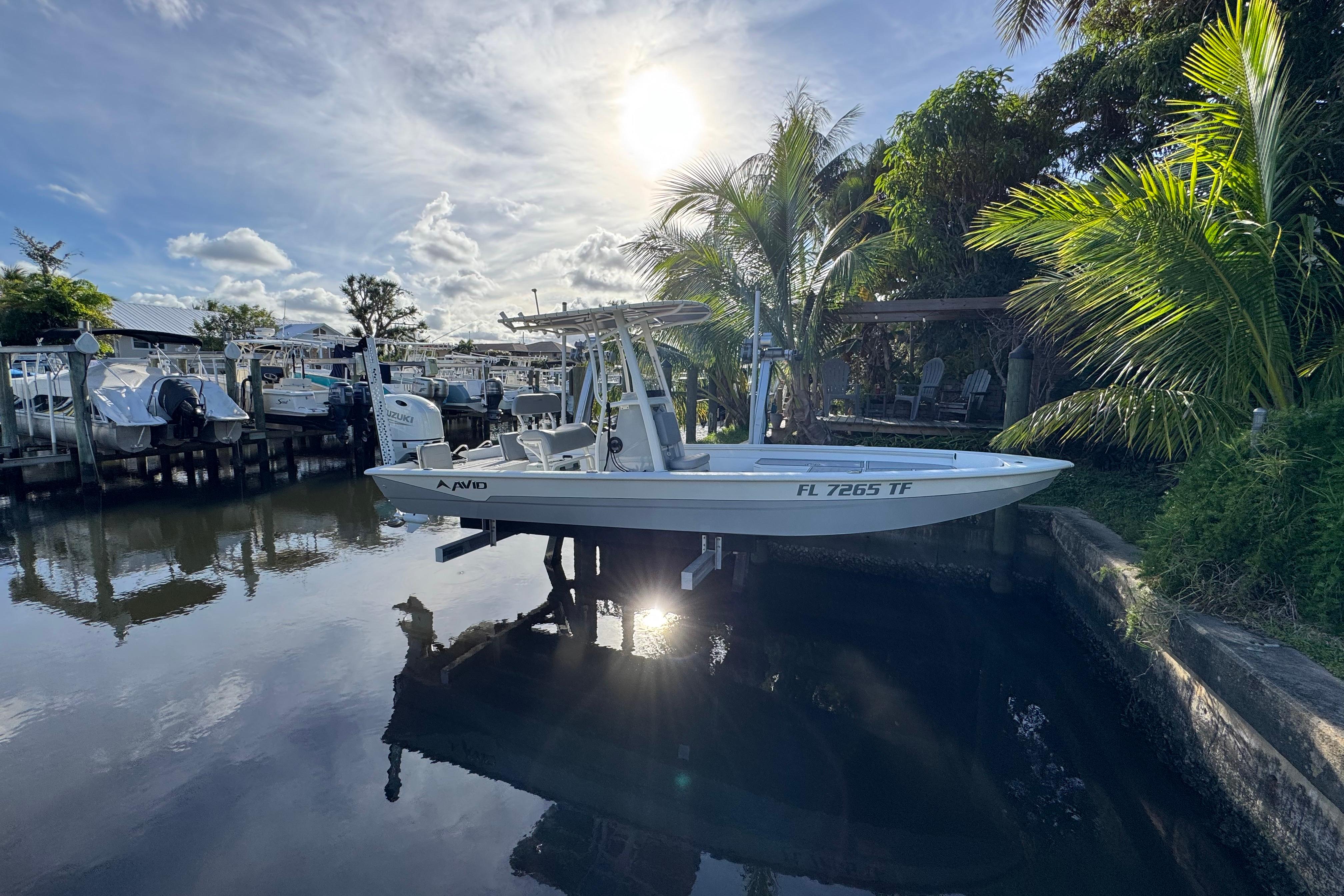 2022 Avid 23 FS Magnum boat docked by palm trees under a bright sun.