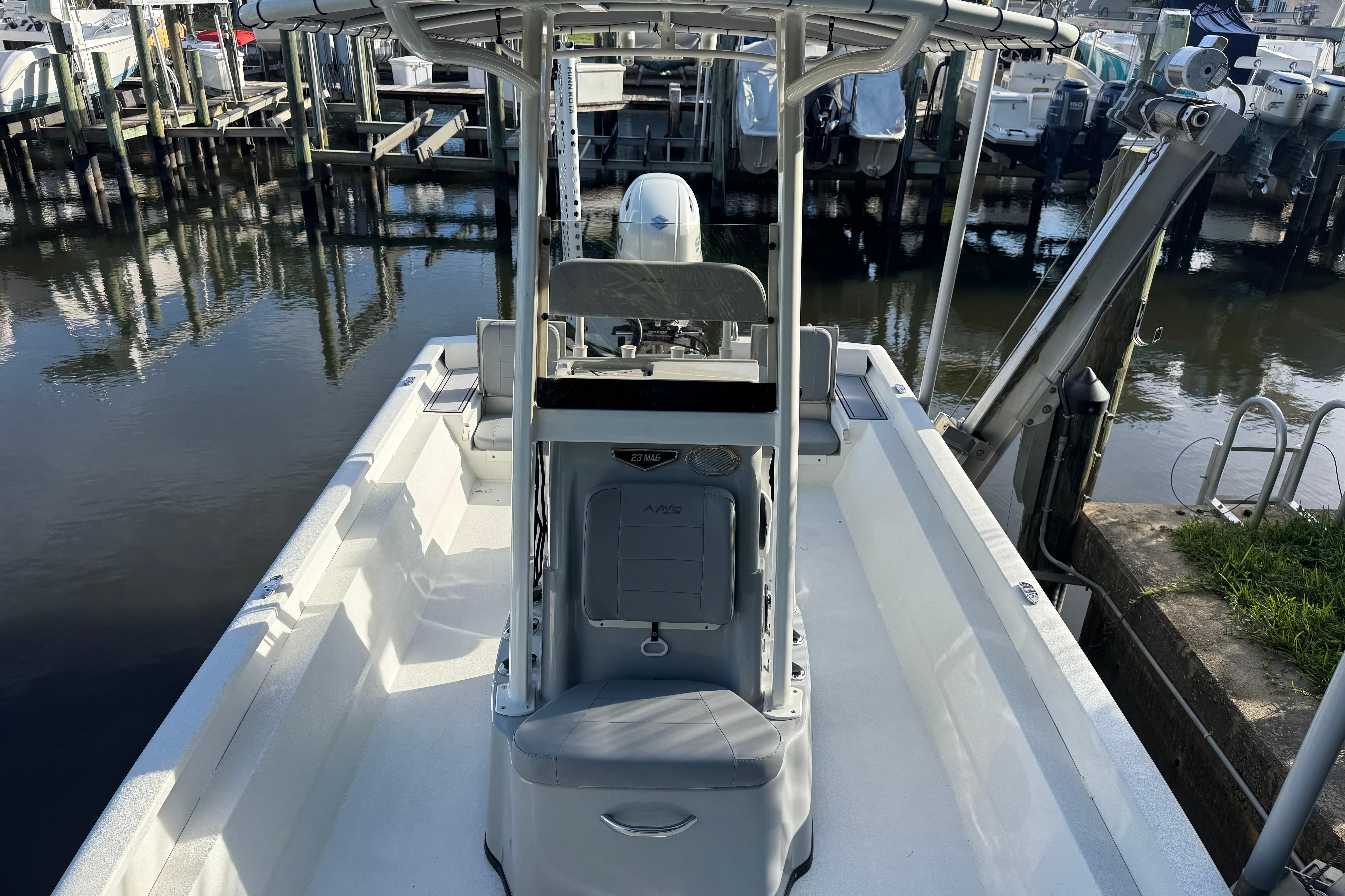 2022 Avid 23 FS Magnum boat docked at marina, showcasing spacious deck and seating.
