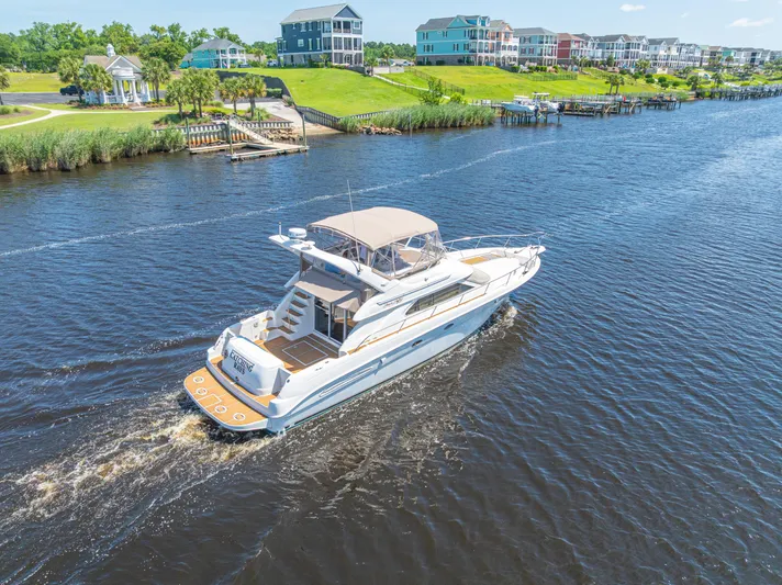  Yacht Photos Pics 1999 Sea Ray 450 Express Bridge cruising on a scenic river near waterfront homes.