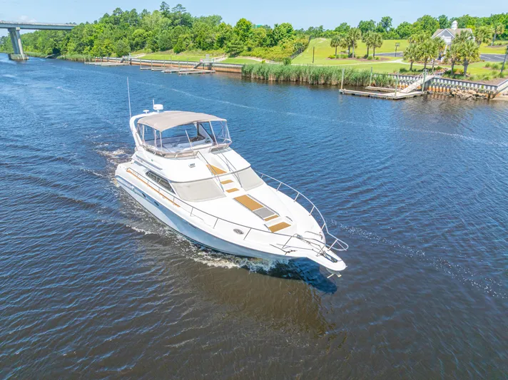  Yacht Photos Pics 1999 Sea Ray 450 Express Bridge yacht cruising on a scenic river.