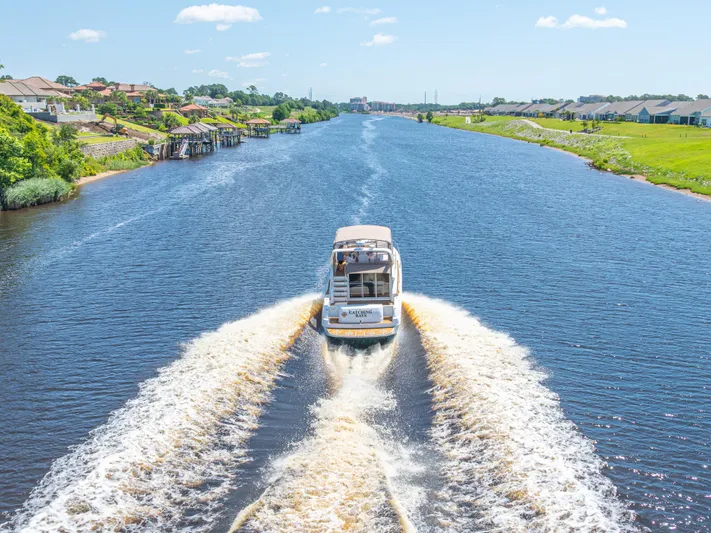  Yacht Photos Pics 1999 Sea Ray 450 Express Bridge cruising on a scenic river with waterfront homes.