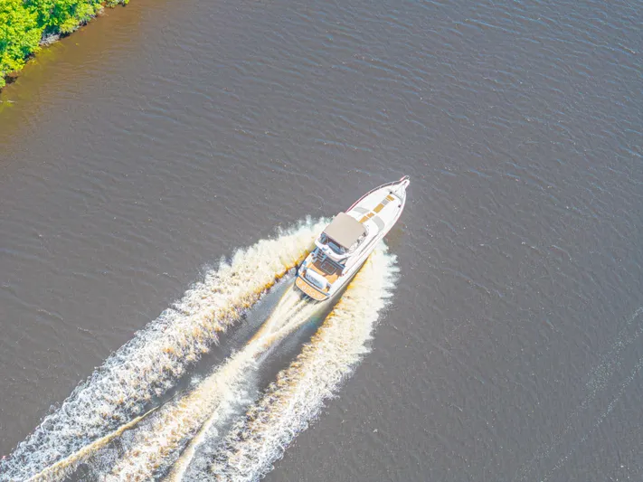  Yacht Photos Pics Aerial view of 1999 Sea Ray 450 Express Bridge cruising on a river.