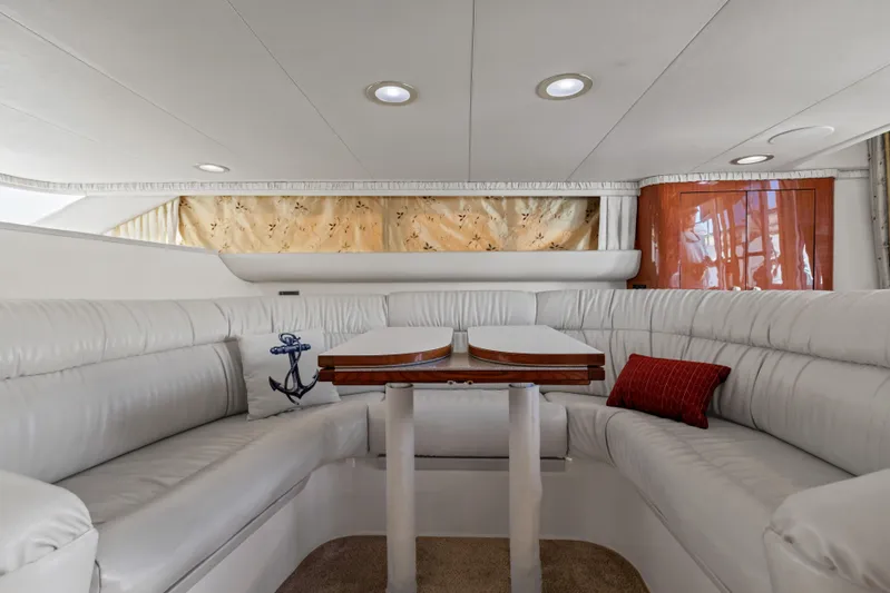  Yacht Photos Pics Luxurious interior of 1999 Sea Ray 450 Express Bridge with white seating and wooden table.