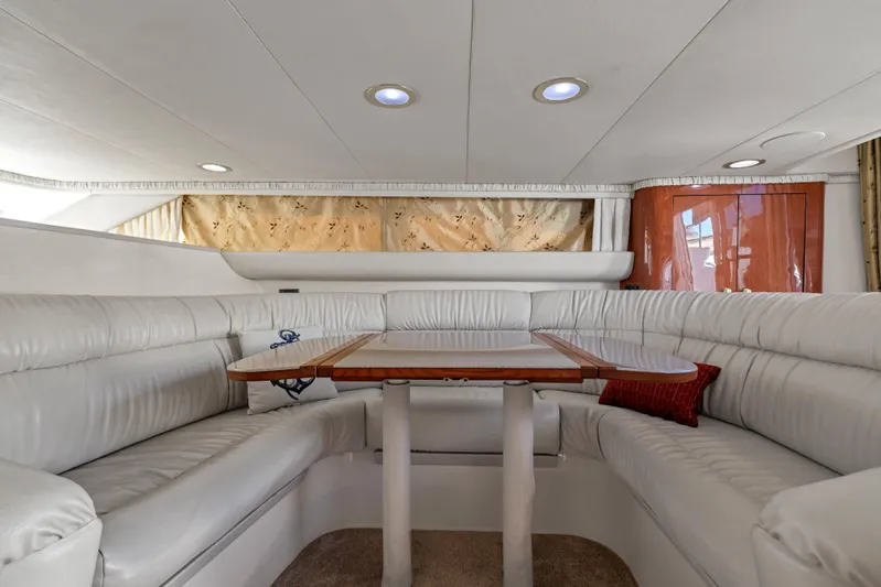  Yacht Photos Pics Luxurious interior of 1999 Sea Ray 450 Express Bridge with white leather seating and wooden table.