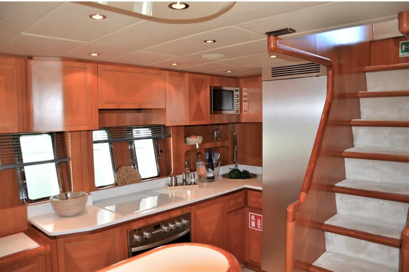  Yacht Photos Pics Luxurious 2003 Mangusta 72 yacht kitchen with wooden cabinetry and modern appliances.