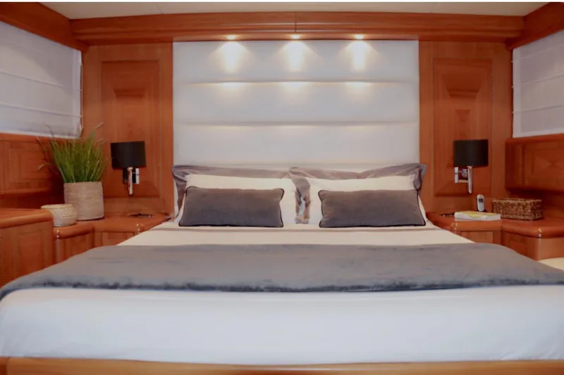 Yacht Photos Pics Luxurious bedroom interior on a 2003 Mangusta 72 yacht, featuring elegant wood paneling.
