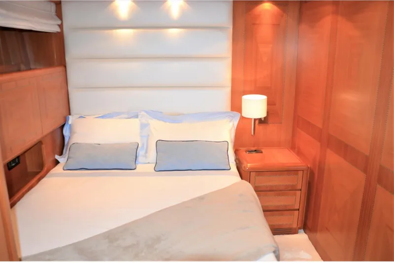  Yacht Photos Pics Luxurious bedroom interior of 2003 Mangusta 72 yacht with elegant wood paneling.