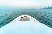 Bow view of 2007 Custom Line 112 yacht cruising towards city skyline.