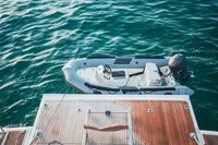 Inflatable boat moored beside a yacht, Custom Line 112, 2007 model, on calm blue water.