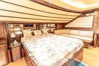 Luxurious 2007 Custom Line 112 yacht bedroom with elegant wood finishes and plush bedding.