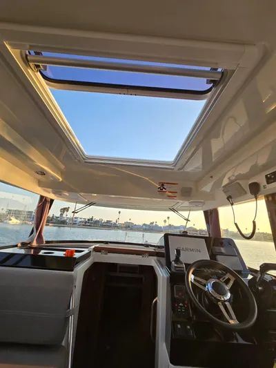 Down Time Yacht Photos Pics Interior view of 2020 Jeanneau NC Sport 895 boat with open sunroof and steering wheel.