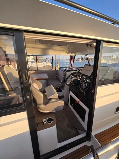 Down Time Yacht Photos Pics 2020 Jeanneau NC Sport 895 boat interior with helm, seating, and waterfront view.