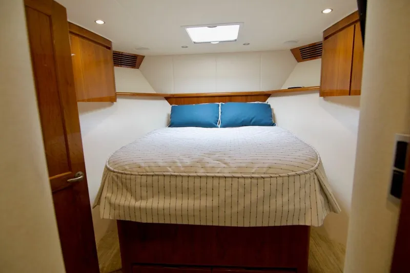 Serenity Now Yacht Photos Pics Interior cabin of 2014 Viking 66 Convertible yacht with cozy bed and wooden accents.