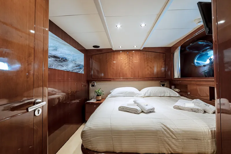 Theion Yacht Photos Pics Luxurious bedroom interior on a 1997 Baglietto 31m yacht, featuring elegant wood paneling.