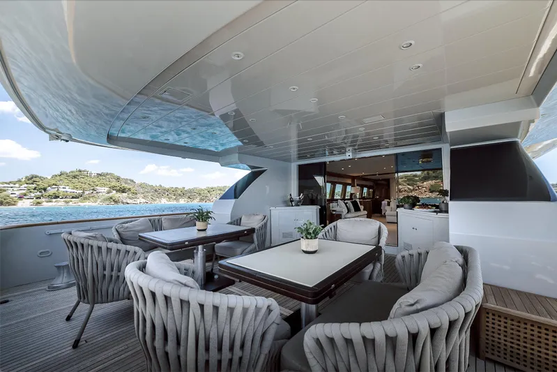 Theion Yacht Photos Pics Luxurious outdoor seating on a 1997 Baglietto 31m yacht, featuring elegant tables and chairs.