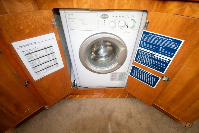 Amazing Grace Yacht Photos Pics Washing machine inside Antares PDQ 44 yacht, 2004 model, with open wooden cabinet doors.