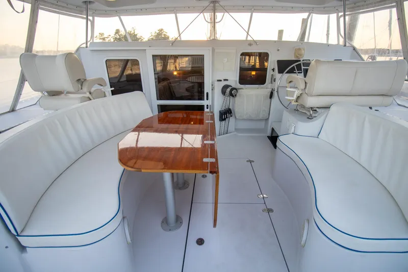 Amazing Grace Yacht Photos Pics Luxurious 2004 Antares PDQ 44 yacht interior with white seating and polished wood table.