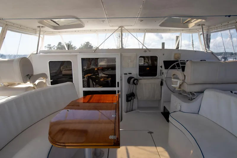 Amazing Grace Yacht Photos Pics Interior view of 2004 Antares PDQ 44 yacht with white seating and wooden table.