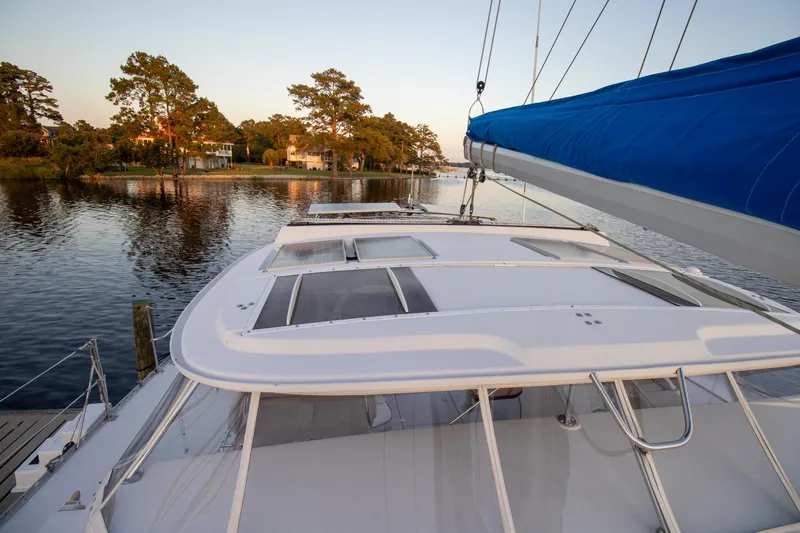 Amazing Grace Yacht Photos Pics Sailing yacht Antares PDQ 44, 2004 model, docked by serene waterfront with trees.