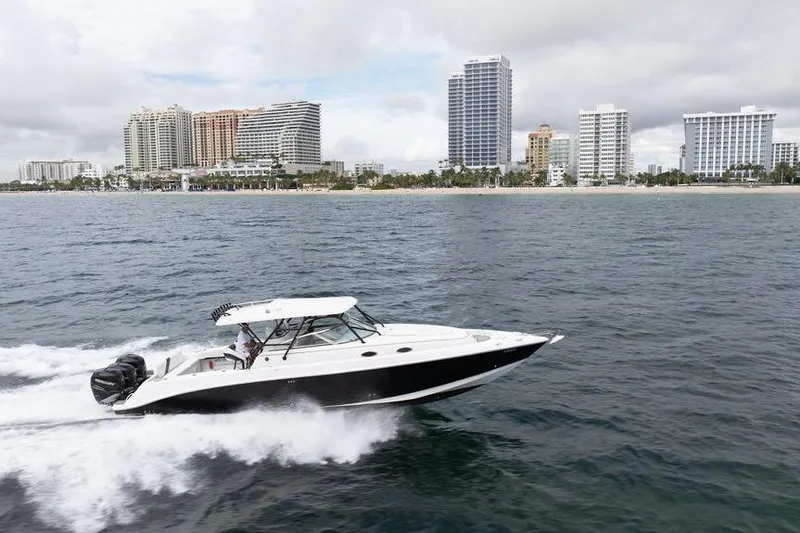  Yacht Photos Pics 2008 Donzi 38 ZSF boat cruising near a city skyline on a cloudy day.