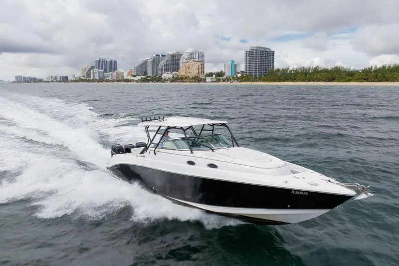  Yacht Photos Pics 2008 Donzi 38 ZSF boat cruising near a city skyline on a cloudy day.