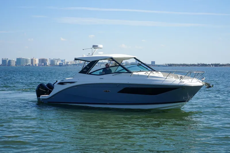 Capstone I Yacht Photos Pics 2023 Sea Ray Sundancer 320 Outboard cruising on calm waters near a city skyline.