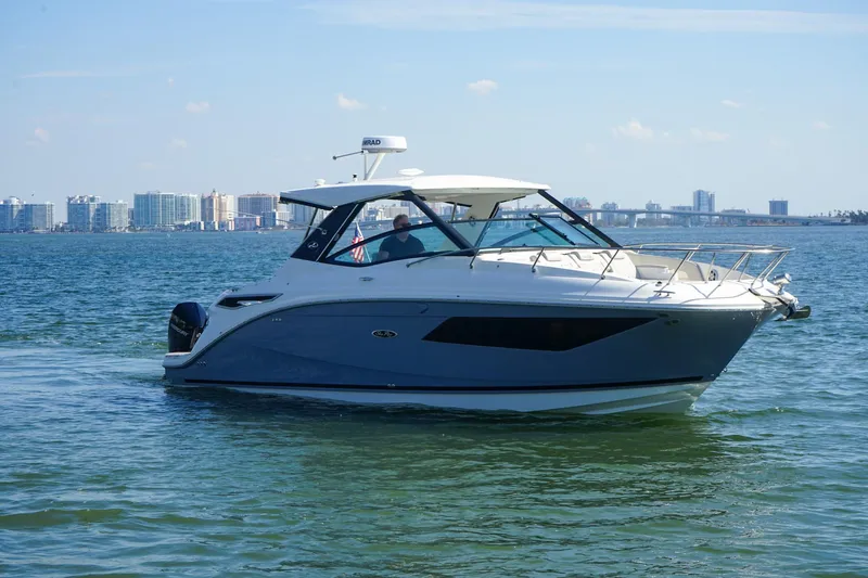 Capstone I Yacht Photos Pics 2023 Sea Ray Sundancer 320 Outboard cruising on water with city skyline in background.