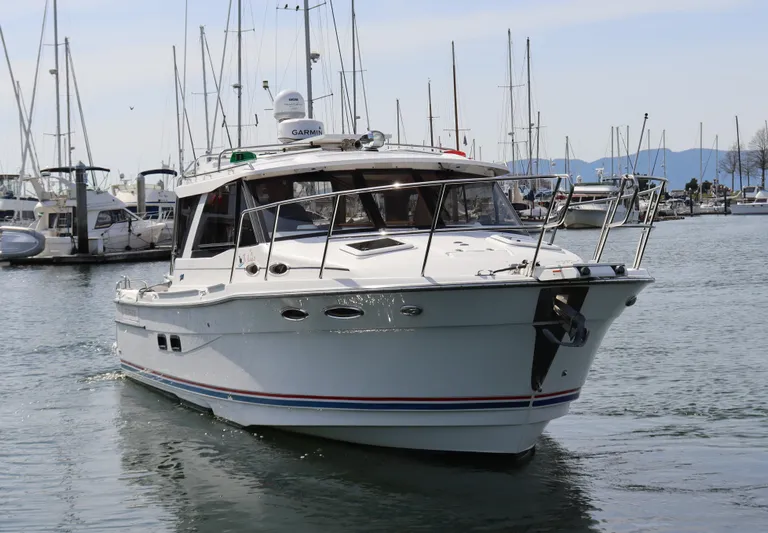 The Islander Yacht Photos Pics 2018 Cutwater C-302 Coupe boat docked in a marina with sailboats in the background.