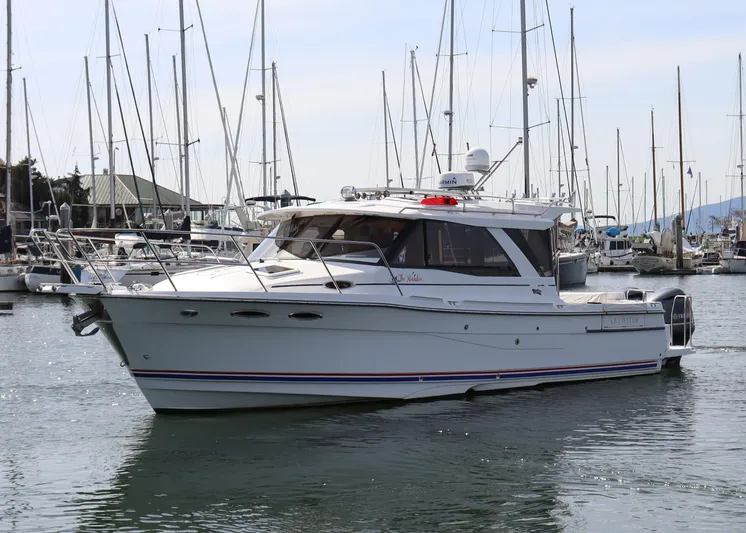 The Islander Yacht Photos Pics 2018 Cutwater C-302 Coupe boat docked in a marina with sailboats in the background.