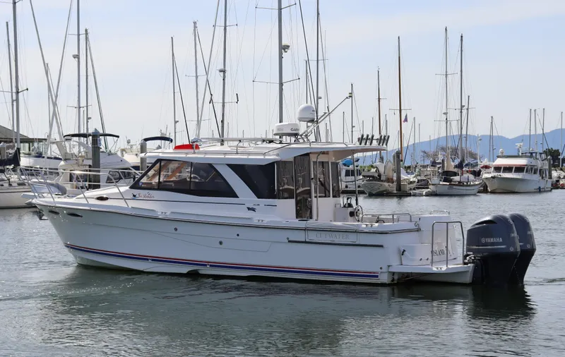 The Islander Yacht Photos Pics 2018 Cutwater C-302 Coupe boat docked in a marina with sailboats in the background.