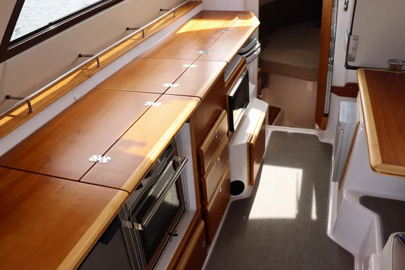 The Islander Yacht Photos Pics 2018 Cutwater C-302 Coupe interior with wooden cabinetry and modern appliances.