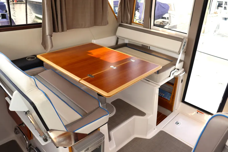 The Islander Yacht Photos Pics Interior of 2018 Cutwater C-302 Coupe with wooden table and cushioned seating.