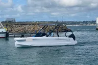 2022 Axopar 22 T-Top boat cruising near rocky shoreline under cloudy sky.