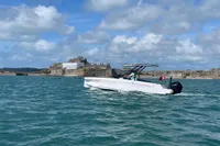 2022 Axopar 22 T-Top boat cruising near a historic coastal fort under a blue sky.