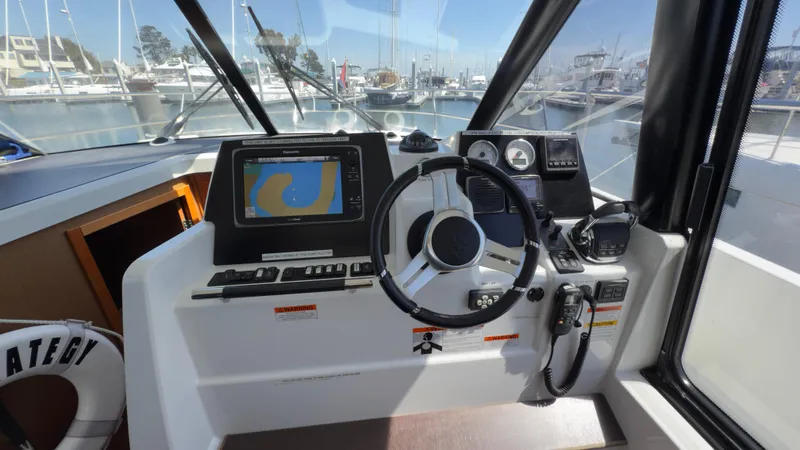  Yacht Photos Pics Helm of 2016 Jeanneau Velasco 37F with navigation system and steering wheel in marina setting.