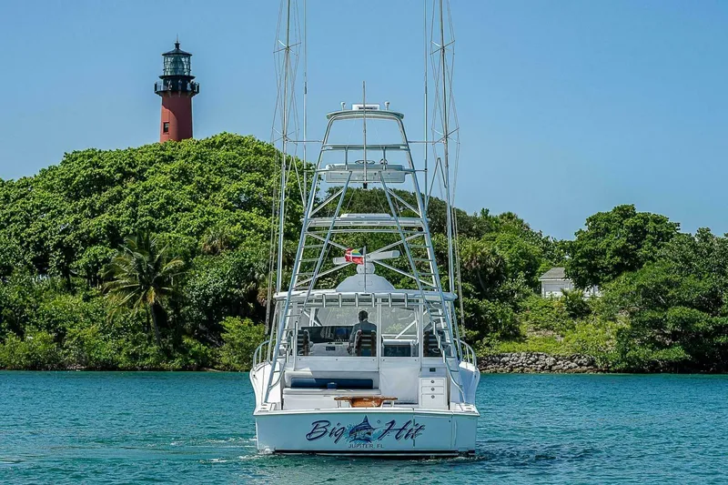 Big Hit Yacht Photos Pics Cabo 40 Express 2020 yacht near lush island with lighthouse in background.