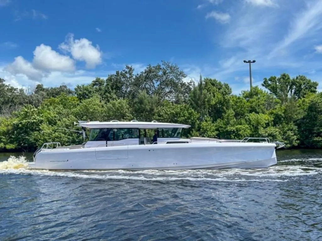 2024 Axopar 45 XC Cross Cabin boat cruising on a river under a clear blue sky.