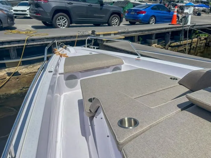  Yacht Photos Pics 2024 Axopar 45 XC Cross Cabin boat with cushioned seating, docked near vehicles.