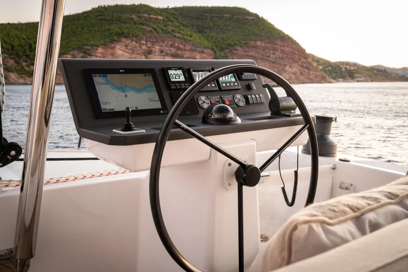  Yacht Photos Pics Steering console of 2026 Bali 5.8 yacht with navigation screens, near scenic coastline.
