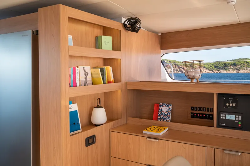  Yacht Photos Pics Modern interior of Bali 5.8 yacht, featuring wooden shelves, books, and ocean view through window.