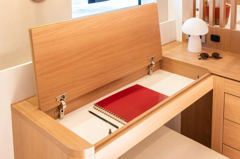  Yacht Photos Pics Modern wooden desk with hidden storage, featuring a notebook and pen, in a Bali 5.8, 2026 model.