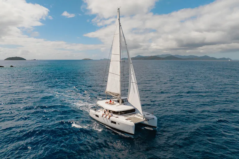 Island Riff Yacht Photos Pics 2025 Lagoon 42 catamaran sailing in open sea under clear skies.