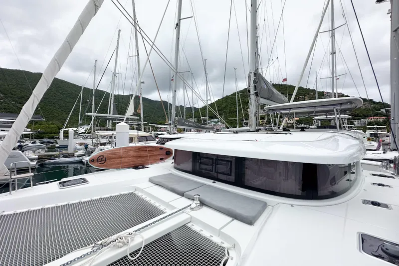 Island Riff Yacht Photos Pics 2025 Lagoon 42 catamaran docked in a marina with lush green hills.