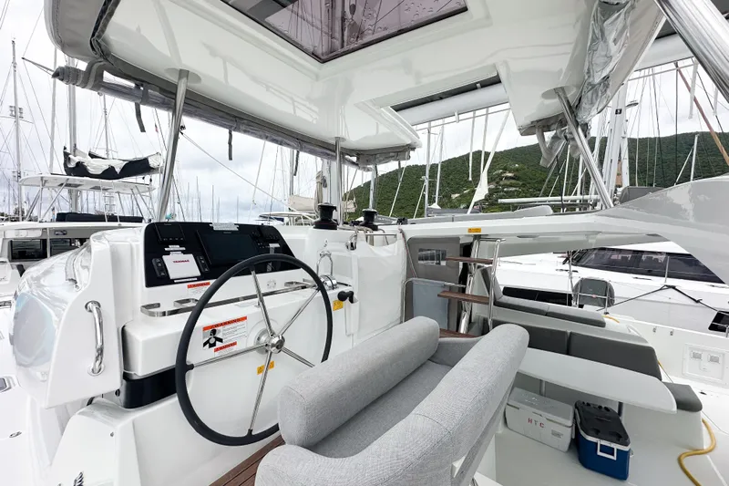Island Riff Yacht Photos Pics 2025 Lagoon 42 yacht cockpit with modern steering and seating, docked in a marina.