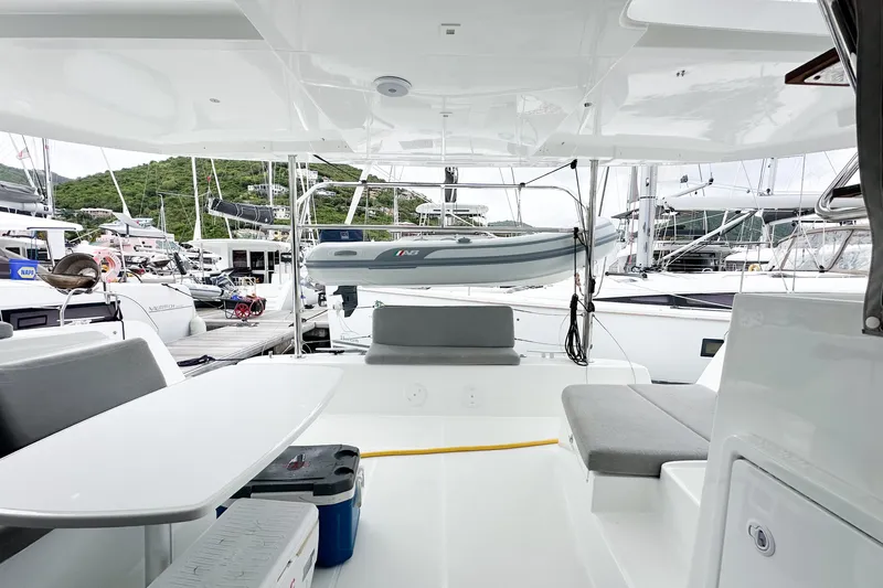 Island Riff Yacht Photos Pics 2025 Lagoon 42 yacht interior with seating, table, and docked boats in background.