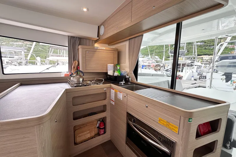 Island Riff Yacht Photos Pics Modern kitchen interior of 2025 Lagoon 42 yacht with sleek wood finish and appliances.
