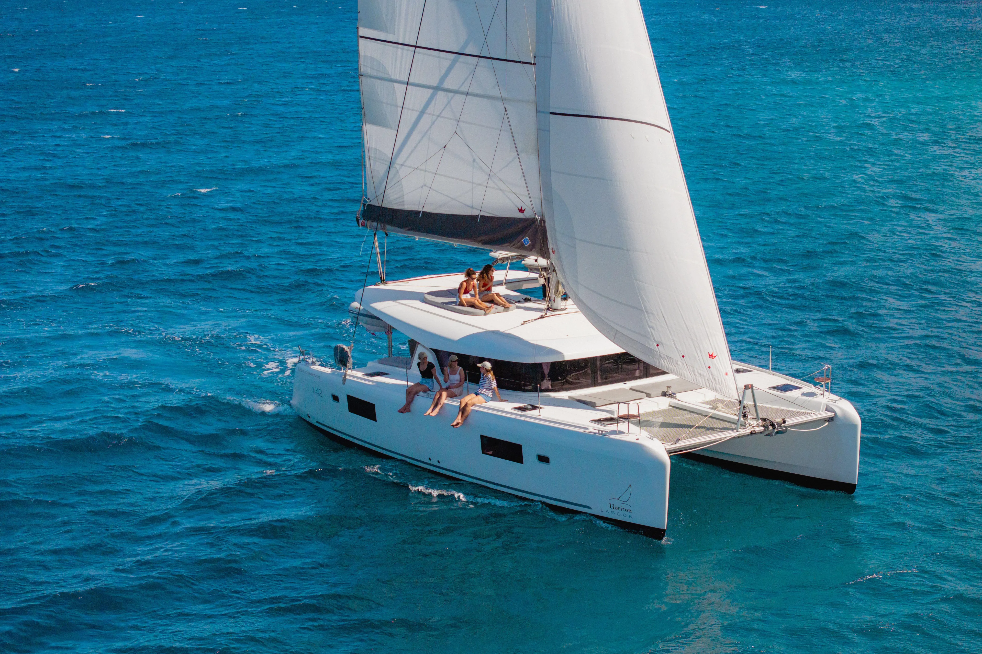Island Riff Yacht Photos Pics 2025 Lagoon 42 catamaran sailing on clear blue ocean waters.