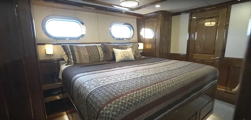Jackpot Yacht Photos Pics Luxurious bedroom in Christensen 2020 yacht with large bed and porthole windows.