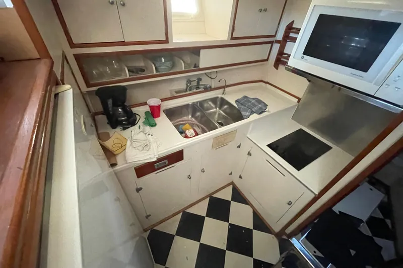 Mnm Yacht Photos Pics 1958 Huckins Seafarer kitchen with checkered floor, sink, microwave, and coffee maker.