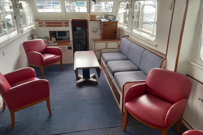 Mnm Yacht Photos Pics Interior of a 1958 Huckins Seafarer yacht with red chairs and a blue sofa.